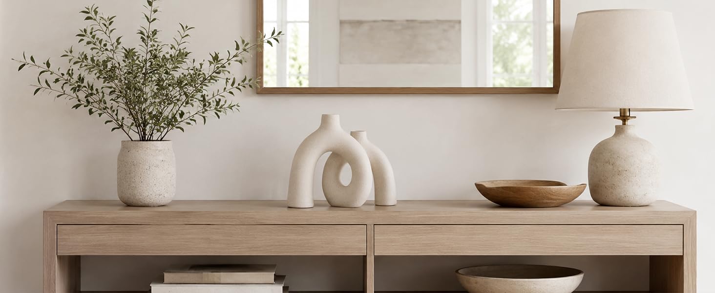 Cream ceramic donut vase displayed on a wooden console table in a neutral entryway setting.