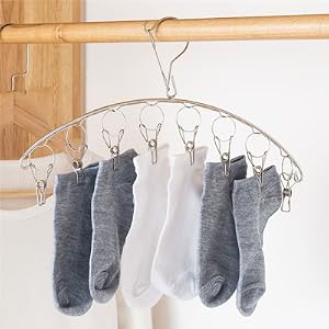 Wire clothing hanger with multiple clips displaying gray and white socks hanging to dry.