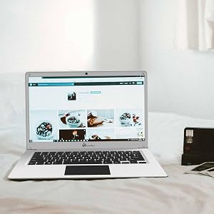 Silver laptop displaying a webpage with multiple images, positioned on white surface with minimal surrounding items.