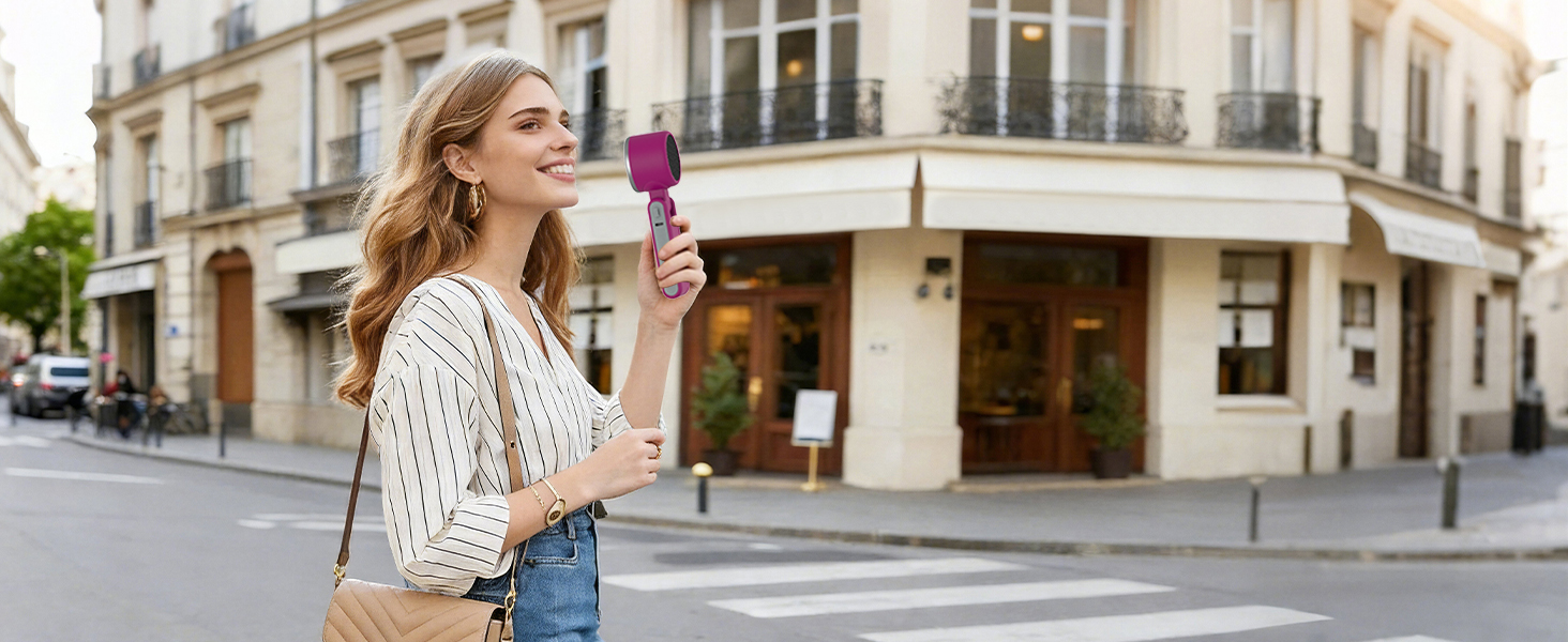 Woman walking in city holding magenta handheld fan stylish mini fan for holiday travel cooling