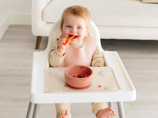 Baby enjoying food in high chair with Prep silicone placemat during happy feeding moments.