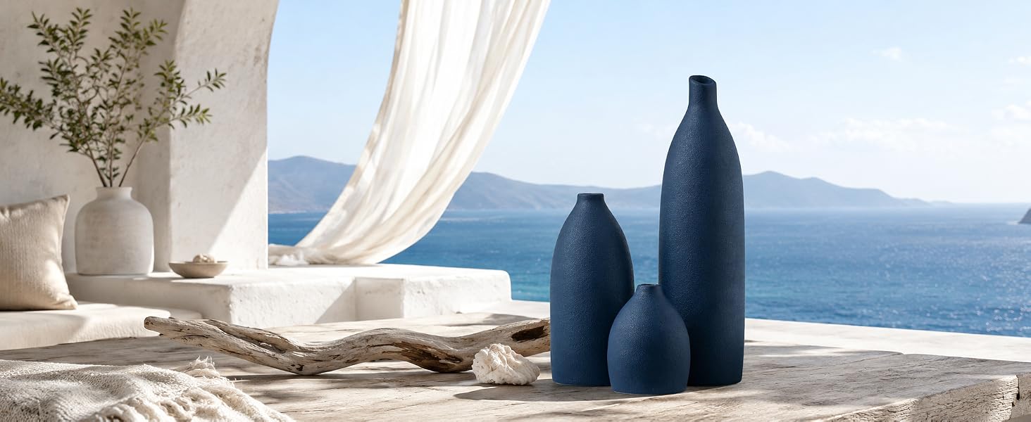 Matte navy blue vase set on an entryway console with woven accents, mirror, and ocean view.