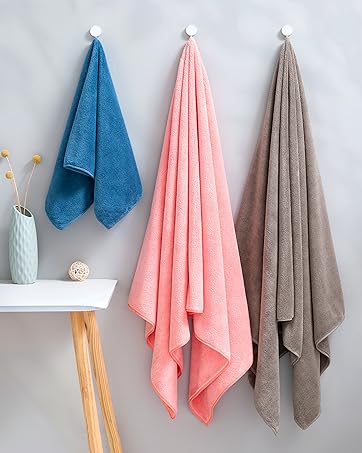 Series of plush towels in blue, pink, and gray colors hanging on wall-mounted hooks. Shows different arrangements and hanging positions of the towels.