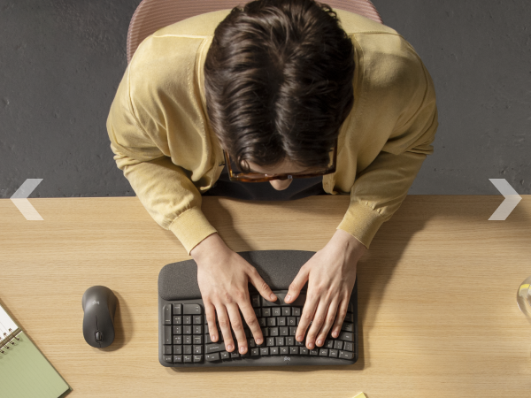 zoom of a man typing on wave keys for business wireless ergonomic compact keyboard