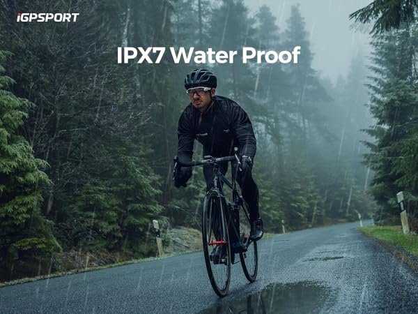 Cyclist riding in rain on forest road, demonstrating IPX7 waterproof rating, wearing dark cycling gear against misty woodland backdrop.