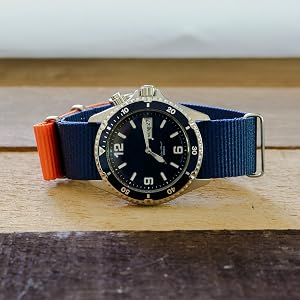 Navy Blue and Orange Color Block Nylon Watch Band on Blue Watch on Wood Background