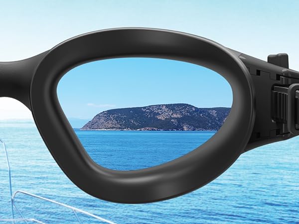 Close-up of black-framed swimming goggles. Lens shows clear view of an island in blue water, demonstrating clarity and field of vision.