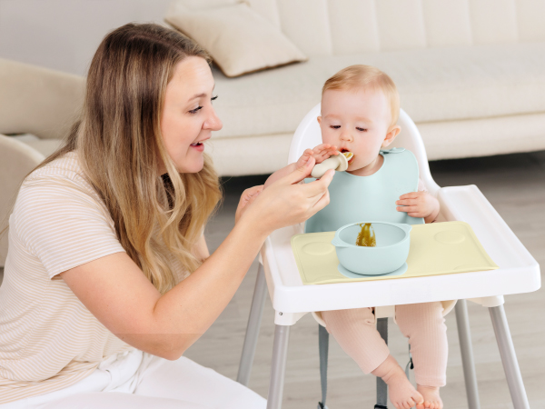 Parent feeding baby using Prep silicone placemat on high chair tray for clean mealtime routine