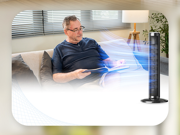 man sitting on a couch with a fan next to him