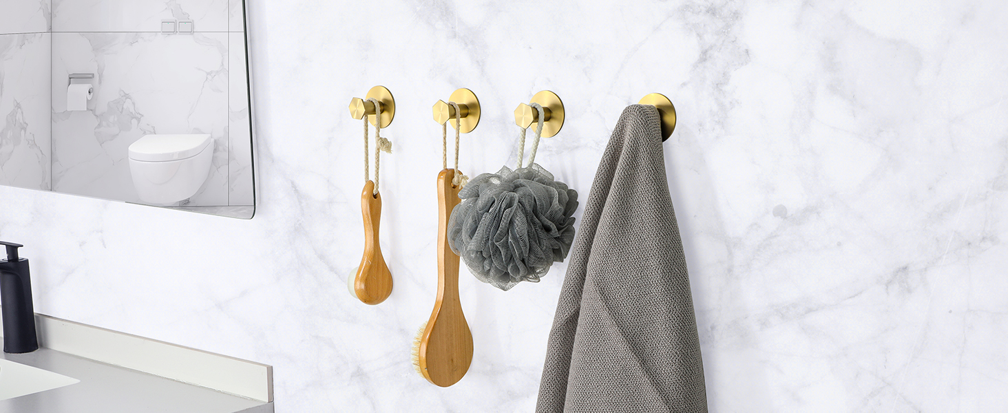 Wall-mounted hooks featuring golden spoon-shaped decorative hangers with gray towel and cleaning accessories displayed.