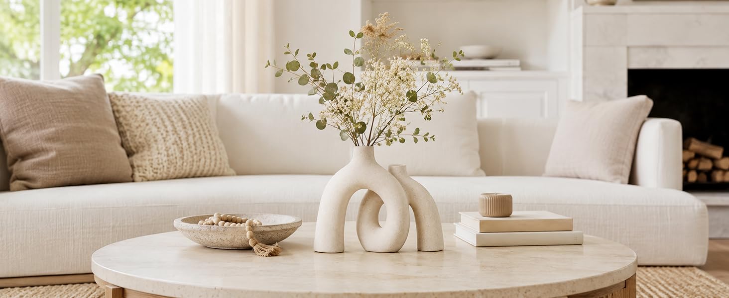 Cream ceramic donut vase with flowers on a living room coffee table.