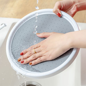 Hands demonstrating cleaning or maintenance of a gray circular filter or mesh component with white frame, water droplets visible.