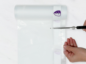 Hands cutting a plastic roll with scissors