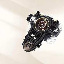 Close-up technical product photo of a black plastic automotive component featuring a circular lens or sensor housing with internal mechanical elements visible.