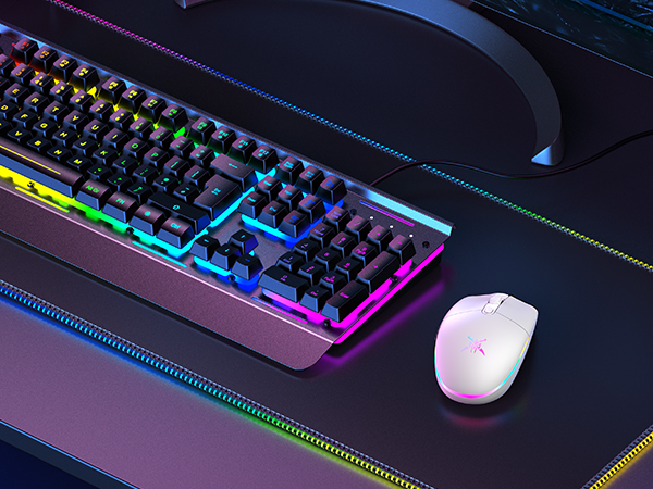 Gaming keyboard with RGB backlighting and color-shifting edges, accompanied by a white wireless mouse on a dark surface with RGB border illumination.