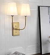 Elegant wall-mounted double sconce with gold-toned metal frame and two white fabric lampshades, shown in a home interior setting.