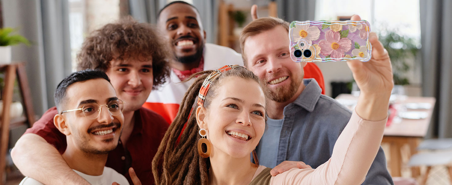 Group of people posing together while one person holds up a smartphone, seemingly taking a group selfie in an indoor setting.