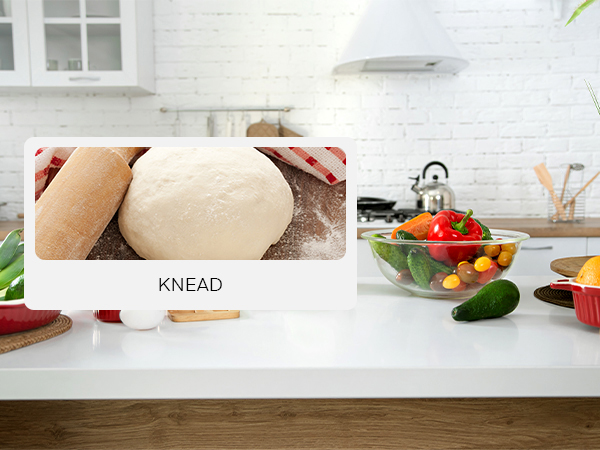 a kitchen counter with a dough and a bowl of vegetables.