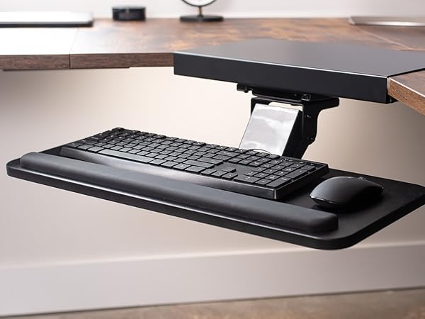 Black keyboard tray extended from corner desk