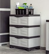 3 drawer plastic storage cabinet in a garage with a cleaning supply basket on top of the cabinet