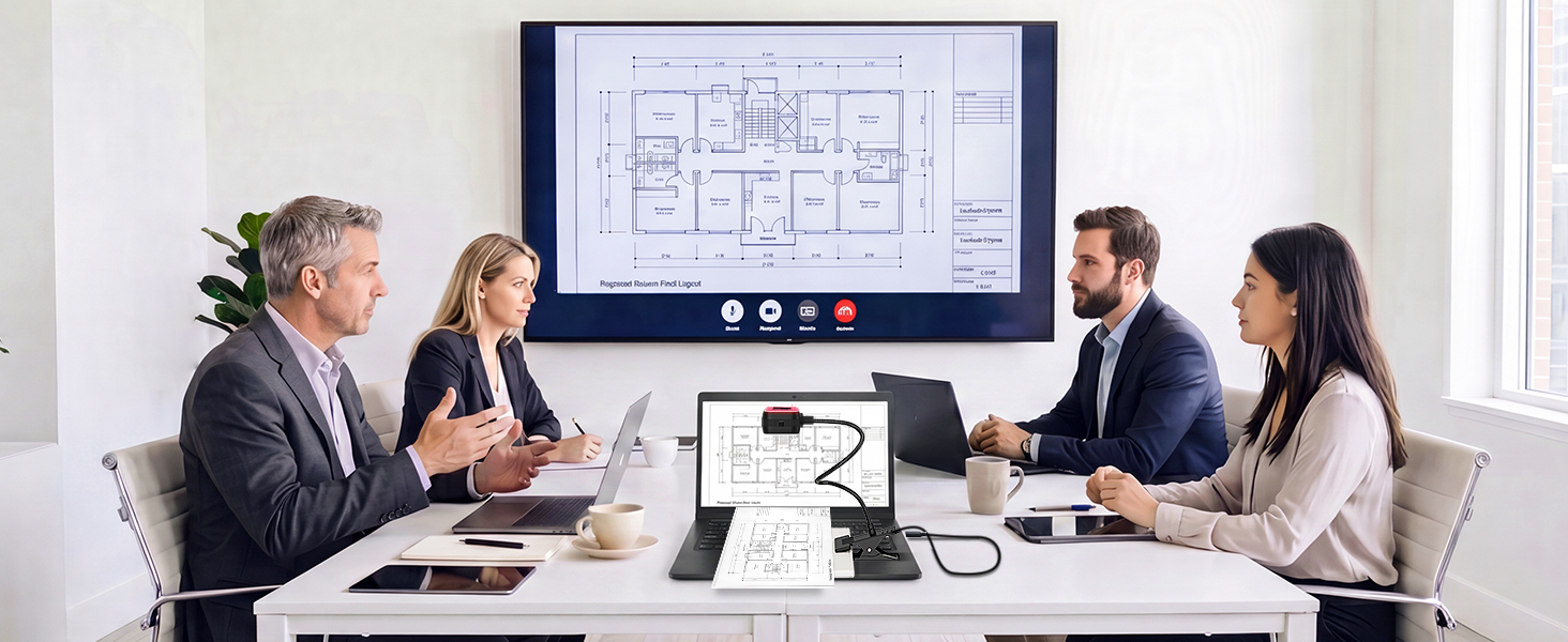 Four professionals seated around conference table in office setting, viewing digital design on mounted monitor screen.