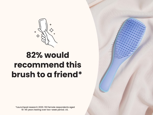 A blue ultimate detangler brush laying on fabric with a positive review text overlay.
