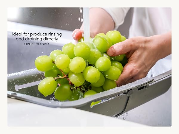 Sink colander expanded across sink rinsing fruit and produce while draining