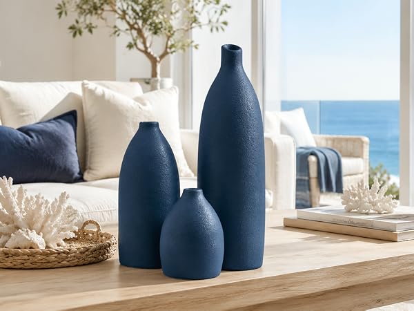 Navy blue bullet-shaped vase set on a coastal kitchen counter with ocean view and shells.