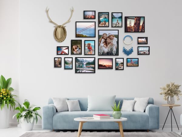 Living room wall gallery featuring multiple framed photos arranged around decorative deer head mount, above light blue sofa with throw pillows.