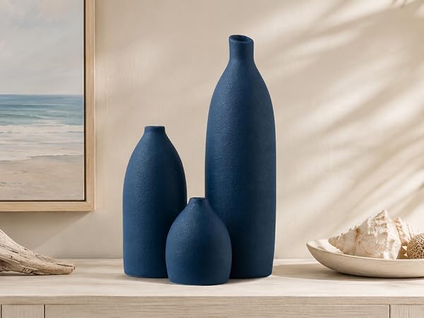 Navy blue bullet-shaped vase set with driftwood, coral, and shells for coastal decor.