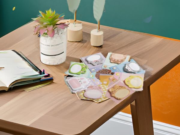 A wooden desk with the product and office supplies scattered around.