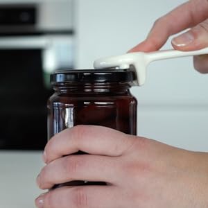 Person popping open lid of jar with jarkey