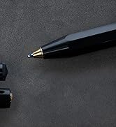 Close-up shot of a black pen or writing instrument against a dark gray textured background, photographed from an angled perspective.