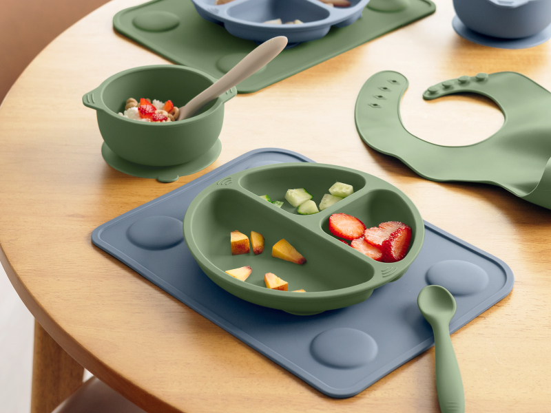 Prep silicone placemats with divided plate, bowl, spoon, and baby feeding accessories on table setup