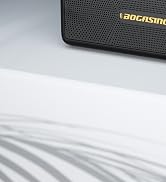 Corner of a black textured electronic device or speaker with 'BOCASING' printed in gold lettering on its surface.