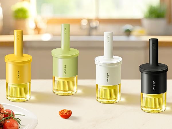 Four colorful kitchen gadgets with cylindrical tops and ribbed glass bottoms. Devices in yellow, green, white, and black, displayed on counter with tomatoes nearby.