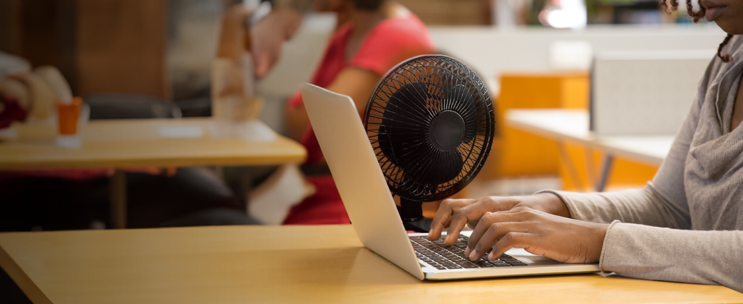 Compact clip-on fan securely attached to desk, providing quiet and efficient personal cooling