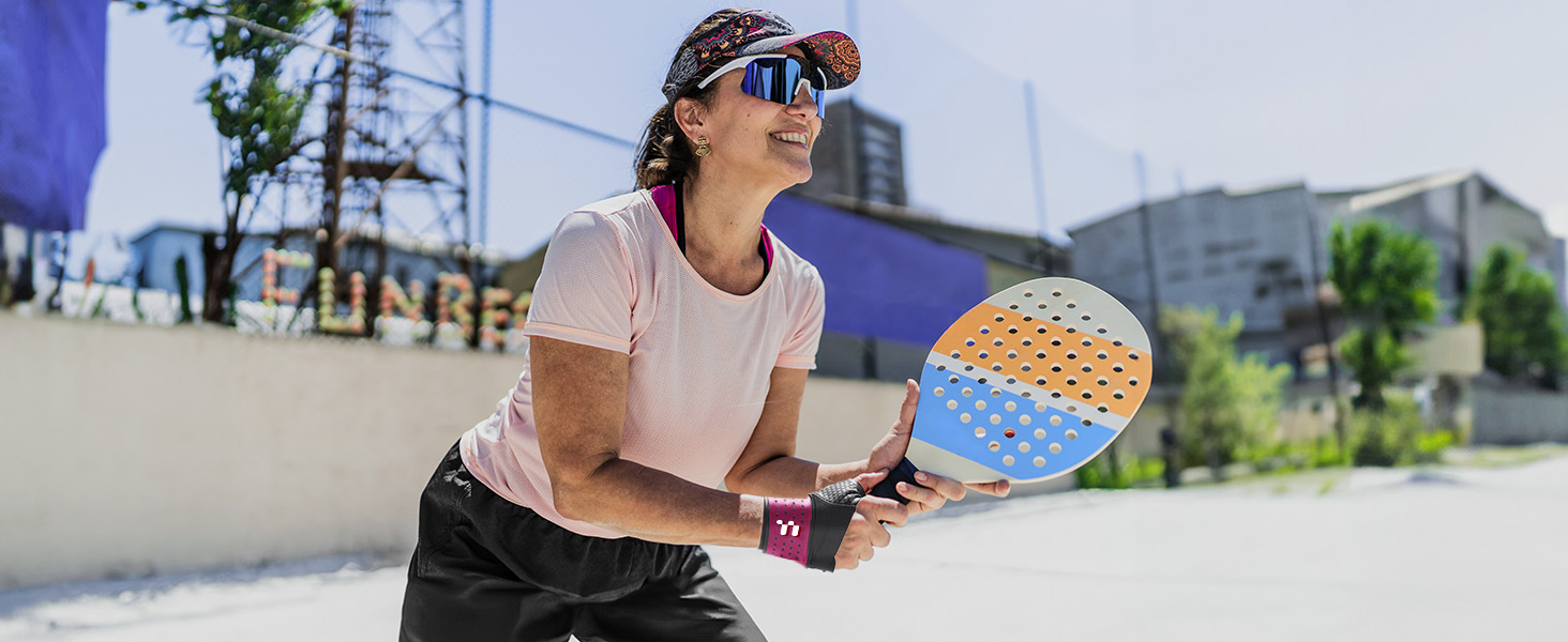 Padel racket with honeycomb pattern visible on its face, being held in ready position during outdoor play.
