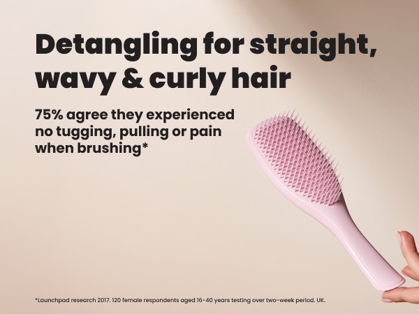 A hand holding a pink ultimate detangler brush.