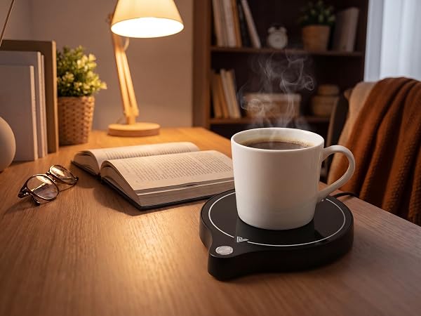 ZenthermoRui coffee mug warmer on desk with steaming mug, book and lamp in background
