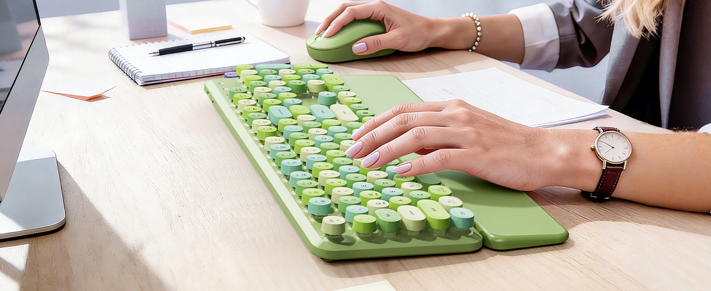 Close-up of hands using green keyboard with wrist rest and mouse on a work desk