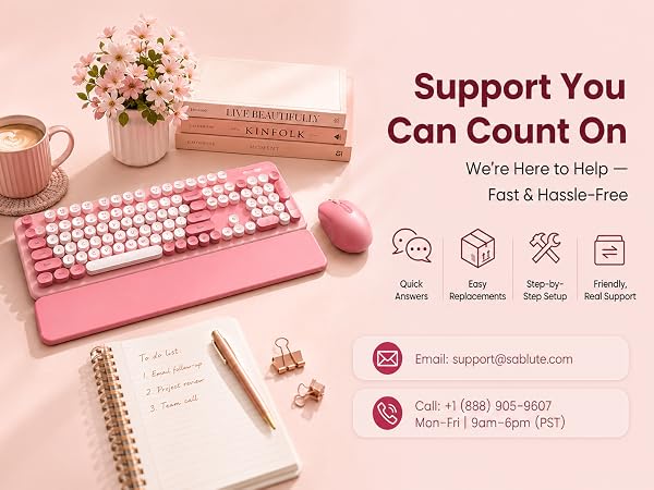 Pink keyboard and matching mouse with wrist rest beside Sablute help details on a blush desk.