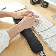 Close-up sequence showing hands using an ergonomic wrist rest pad while typing on a white keyboard against a wooden desk surface.
