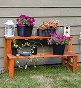 2 tier wood plant stand with lush flowers and garden decor in backyard against exterior wall