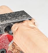 Close-up of someone scraping or smoothing a beige surface with a dark speckled tool, with red element visible in corner.