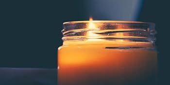 lit candle in a mason jar with dark background