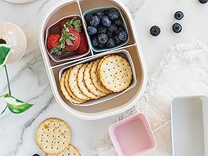 Silicone baking cups in a lunch box sorting snacks, crackers, fruit