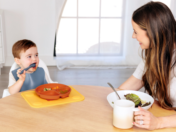Baby eating independently with Prep silicone placemat and bowl during everyday mealtime at home