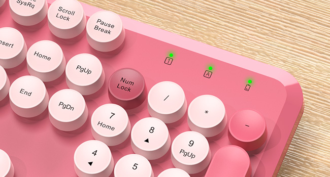 Close-up of pink retro keyboard number pad with indicator lights and round keycaps.