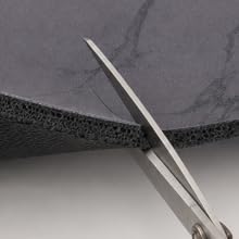 Black marble coffee mat being cut with scissors for a custom fit.